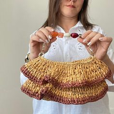 a woman is holding a straw purse and beaded it with two beads in her hands