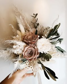 a person holding a bouquet with flowers and feathers