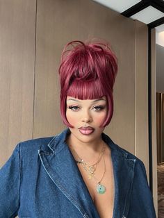 a close up of a person with red hair wearing a denim shirt and necklaces