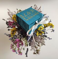 a bouquet of wildflowers is wrapped in a blue box with the date and year on it