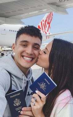 a man and woman hugging each other in front of an airplane with their passports