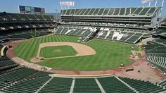 an empty baseball stadium filled with lots of green seats and people standing on the sidelines