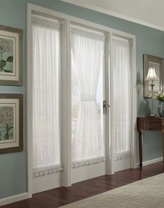 the interior of a bedroom with blue walls and white curtains on the windowsills