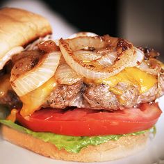 a hamburger with onions, cheese and tomato