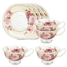 a set of four tea cups and saucers with pink flowers on the rims