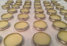 rows of small round tins sitting on top of a table covered in white cloth