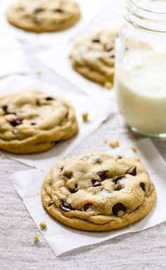 chocolate chip cookies and a glass of milk on a table with napkins next to them