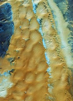 an aerial view of the earth's terrain and its surrounding land area, with blue patches in the sand