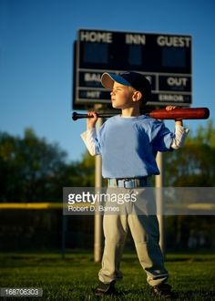 a young boy holding a baseball bat in front of a sign