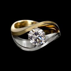 a gold and silver ring with a diamond in the center on a black background photo