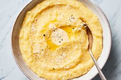 a bowl filled with mashed potatoes topped with butter and seasoning next to a spoon