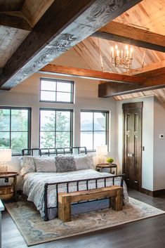 a large bed sitting under a wooden beam in a bedroom next to two windows and a door