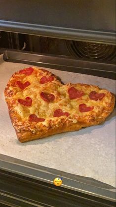 a heart shaped pizza sitting on top of an oven