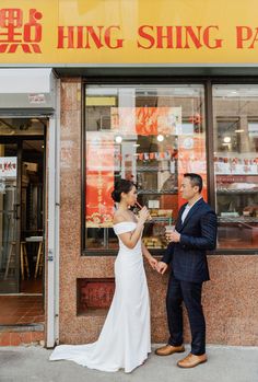 a man and woman standing in front of a store holding each other's hands