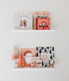 two white shelves filled with books and christmas decorations on top of each shelf in front of the wall