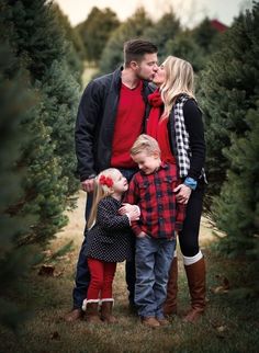 a man and two children standing next to each other in a christmas tree farm