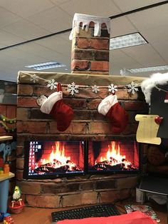 an office cubicle decorated for christmas with fireplace and stockings