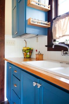 a kitchen with blue cabinets and wooden counter tops