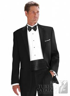 a man in a tuxedo is standing with his hands in his pockets and looking at the camera