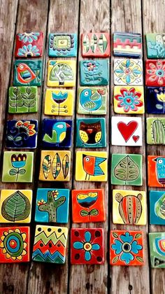 many colorful tiles are arranged on a wooden table with flowers and birds painted on them