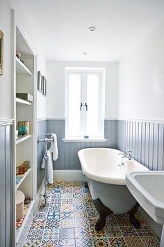 a bath tub sitting next to a white sink under a window in a room with blue walls