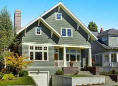 a gray house with white trim on the front and side windows is shown in this image