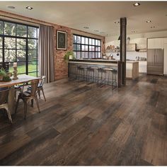 a large open kitchen and dining room area with wood flooring on the walls, windows, and sliding glass doors