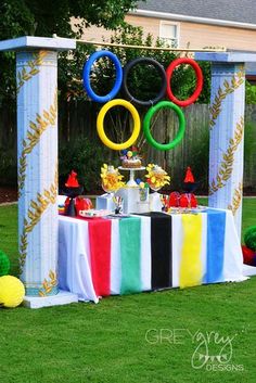 an outdoor party decorated with colorful decorations and decorating items for the olympics theme is shown