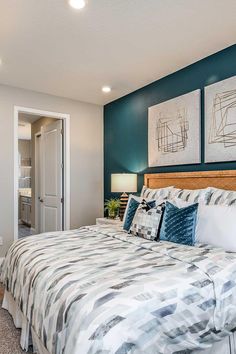 a bedroom with blue walls and white bedding in the corner, along with two paintings on the wall