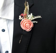 a boutonniere with flowers and feathers on the lapel of a man