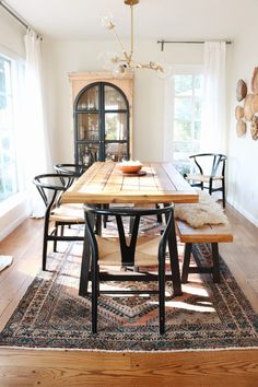 a dining room table with chairs and a rug on the floor