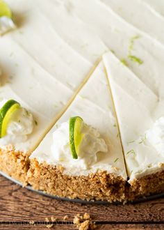 a cake with white frosting and limes on top sitting on a wooden table