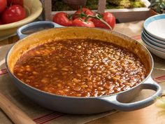 a large pot filled with beans sitting on top of a table next to plates and bowls