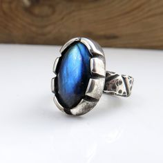 Handmade fine silver ring with a beautiful flashy blue labradorite gemstone. US Ring Size 7. Ring weighs 14.2g including the stone. Labradorite including setting measures 20mm by 13mm. Ring band width: 6mm. All metal parts are handmade using .999 fine silver. Handmade by Mike Summers. We are husband and wife Mike and Annie, making silver jewelry in two uniquely different styles. With a passion for rocks and gemstones, we also cut and polish our own cabochons to use in our creations. We live and work in a tiny cabin in a remote part of Talkeetna in Alaska and it's always a bit of an adventure crossing our creek in a boat to get on the roads to the post office. We have set our dispatch time to 1-2 weeks, and we usually make a visit to the post office once a week all being well. We do not wan Unique Blue Labradorite Ring, Blue Labradorite Moonstone Ring, Labradorite Ring, Silver Jewelry Handmade, Blue Labradorite, Ring Band, Silver Bangles, Handmade Jewellery, Ring Size 7