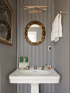 a white sink sitting under a bathroom mirror next to a wall mounted faucet