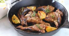 a pan filled with meat and potatoes on top of a table