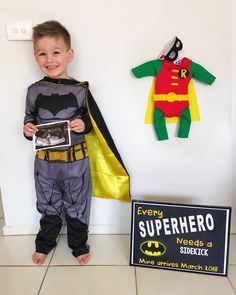 a little boy dressed up as batman and standing next to a sign that says every superhero needs a steekk