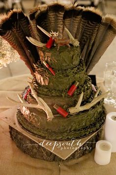 a table topped with a tall cake covered in green frosting next to candles and napkins