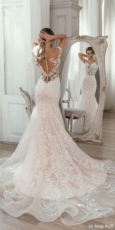 a woman in a wedding dress looking at herself in the mirror with her back to the camera