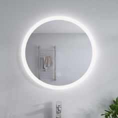 a bathroom with a round mirror on the wall and a towel rack in front of it