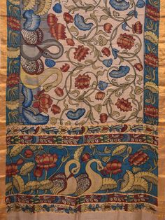 an intricately designed wall hanging with birds and flowers on blue, yellow and red fabric