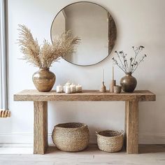 a wooden table topped with baskets next to a mirror