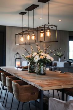 a wooden table topped with lots of flowers and lights hanging from it's ceiling