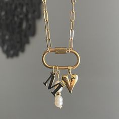 The Keepsake Necklace features a personalized initial charm and a convenient carabiner to easily add any other favorite charms you have. This necklace serves as a special container for all your cherished memories through charms. Featuring: Openable Carabiner with a Gold Plated Stainless Steel Initial Charm, a Long Pearly Charm, & our 18k gold plated Dainty Heart charm. The necklace is 16 inches long. Although this piece is made with water resistant materials, we always recommend to take pieces off before entering water!  while supplies last!  if you are a local customer, we can set up pickup/delivery and get your piece to you sooner!! Chunky Necklace Gold, Gold Charms For Necklace, Carabiner Charm Necklace, Dainty Charm Necklace, Chunky Cross Necklace, Personalized Jewelry For Mom, Boyfriend Jewelry, Memory Necklace, Carabiner Necklace