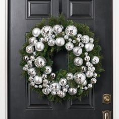 a christmas wreath with silver ornaments hanging on the front door