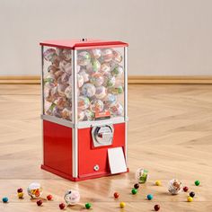 an old fashioned red and white gummy machine with lots of candies scattered around it