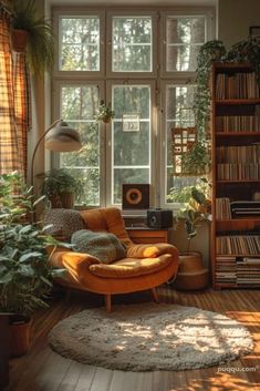 a living room filled with lots of plants and furniture next to a large window on top of a hard wood floor