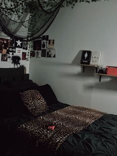 a bedroom with a leopard print comforter and black bedding, hanging pictures on the wall