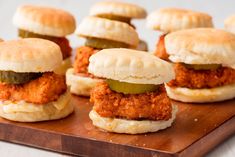 small sandwiches with pickles and cheese are on a cutting board, ready to be eaten