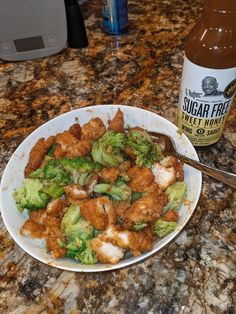 a white bowl filled with broccoli and chicken next to a bottle of sugar free sweet honey